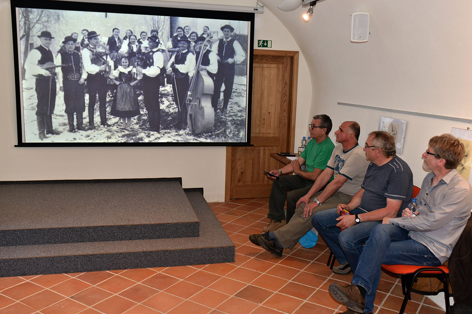 Zleva Jaroslav Landsinger, Petr Záleský, Zdeněk Junek a Robert Malota sledují promítanou ukázku z jejich filmu, po jejímž zhlédnutí budou vzpomínat na natáčení